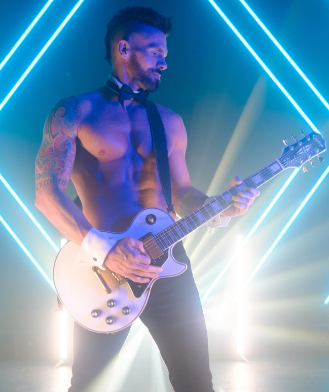 Male dancer from Magic Men Live dressed in full rockstar attire holding a guitar