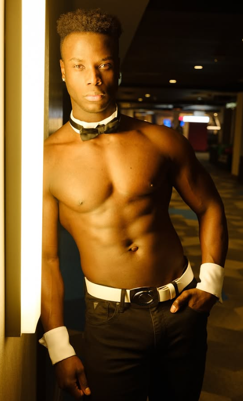 Male stripper dressed as a seductive bartender wearing pants, collar, and white wristbands
